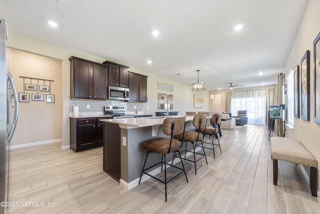 2793 Pointed Leaf Rd, Green Cove Springs, FL 32043 - kitchen featuring light wood-type flooring, open floor plan, dark brown cabinetry, a breakfast bar, and appliances with stainless steel finishes