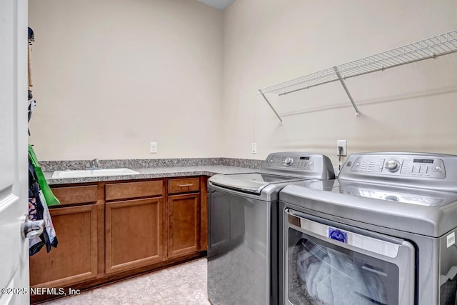 washroom featuring a sink, cabinet space, independent washer and dryer, and light tile patterned floors