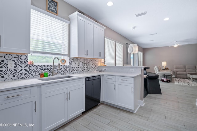 kitchen featuring open floor plan, black dishwasher, light countertops, white cabinetry, and a sink