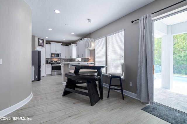 dining area featuring recessed lighting, baseboards, and light wood finished floors