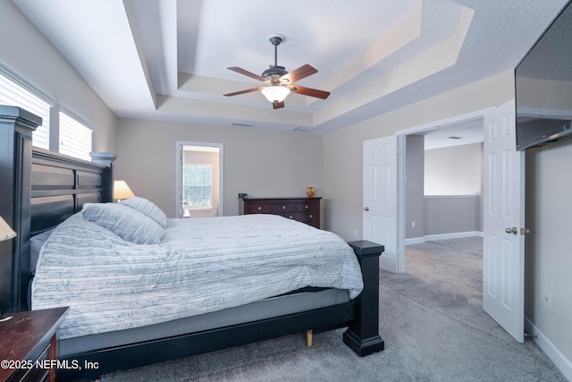 bedroom featuring light colored carpet, a ceiling fan, baseboards, a tray ceiling, and visible vents