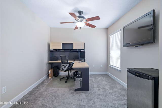carpeted office featuring baseboards and a ceiling fan
