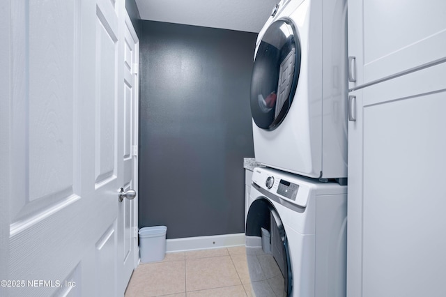 laundry room with baseboards, laundry area, stacked washer / drying machine, and light tile patterned floors