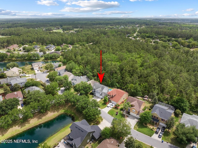 drone / aerial view featuring a water view, a residential view, and a wooded view