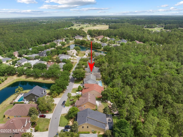 drone / aerial view featuring a water view, a view of trees, and a residential view