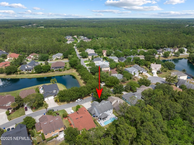 birds eye view of property featuring a forest view, a water view, and a residential view