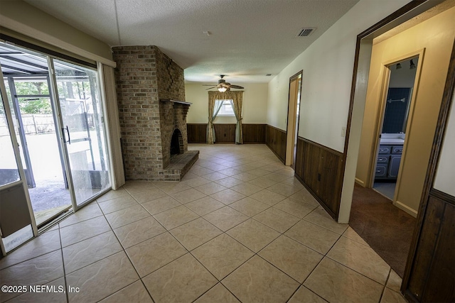 861 Hibernia Forest Dr, Fleming Island, FL 32003 - unfurnished living room with wainscoting, a ceiling fan, a fireplace, light tile patterned floors, and wooden walls