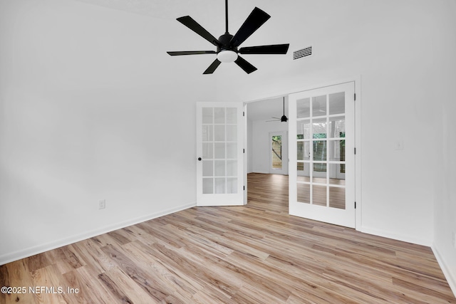 spare room featuring wood finished floors, visible vents, a ceiling fan, french doors, and baseboards