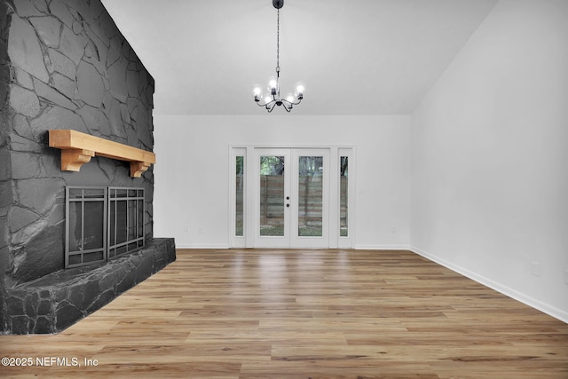 unfurnished living room with a fireplace, wood finished floors, baseboards, and a notable chandelier