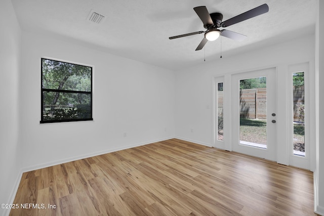 spare room with baseboards, visible vents, light wood-style floors, and ceiling fan