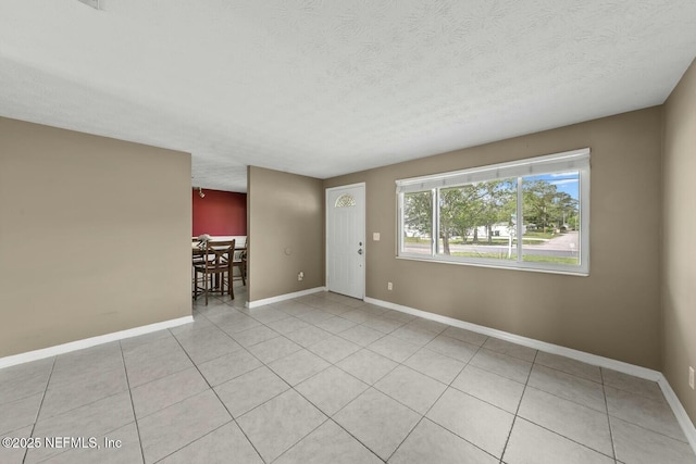 unfurnished room featuring baseboards, a textured ceiling, and light tile patterned floors