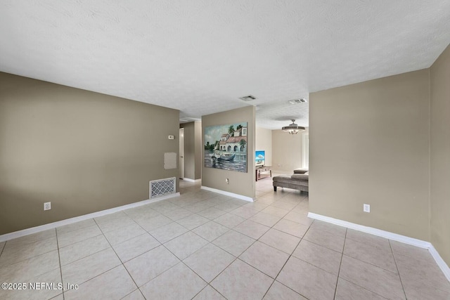 unfurnished room featuring baseboards, light tile patterned flooring, a textured ceiling, and visible vents