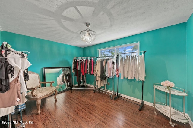 interior space featuring a textured ceiling, baseboards, an inviting chandelier, and wood finished floors