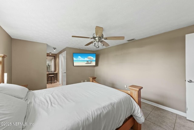bedroom with ceiling fan, visible vents, baseboards, ensuite bathroom, and light tile patterned flooring