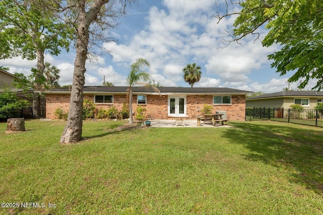 rear view of property featuring fence, french doors, brick siding, a patio area, and a yard