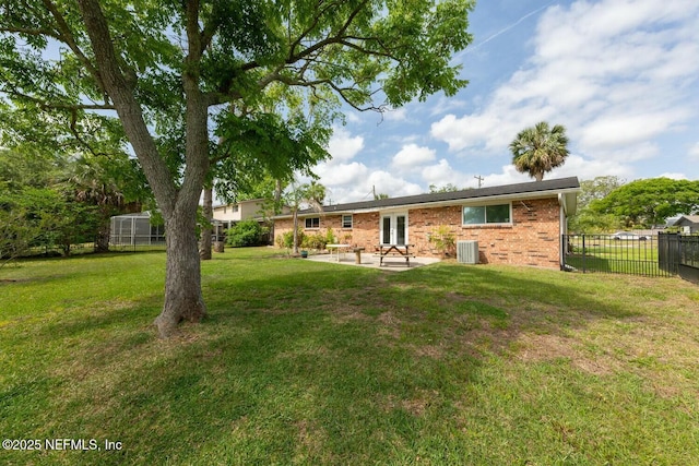 back of house with central AC unit, brick siding, fence, a yard, and a patio