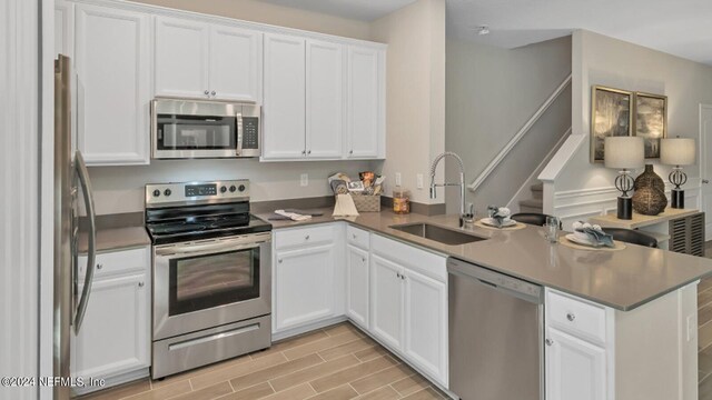 59 Craig Ct, Saint Johns, FL 32092 - kitchen featuring a sink, stainless steel appliances, light wood-style flooring, a peninsula, and white cabinetry