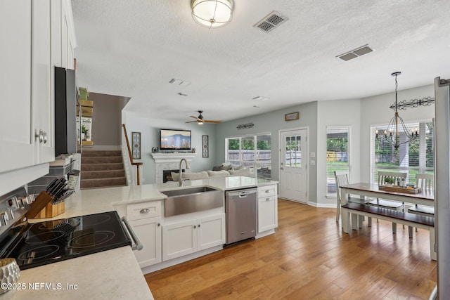 kitchen with dishwasher, a sink, light countertops, ceiling fan with notable chandelier, and open floor plan