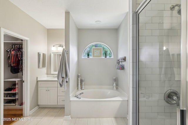 bathroom featuring vanity, tile patterned flooring, a bath, a spacious closet, and a stall shower
