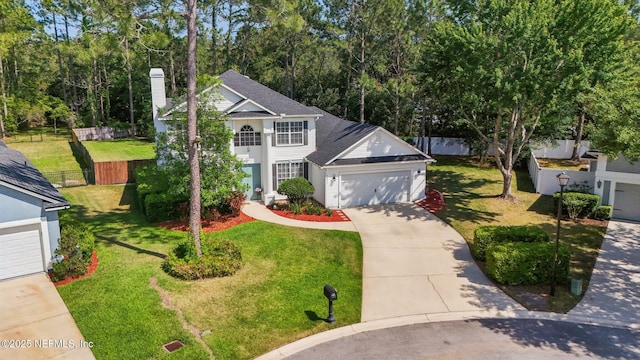 view of front of property with fence, a chimney, concrete driveway, and a front yard