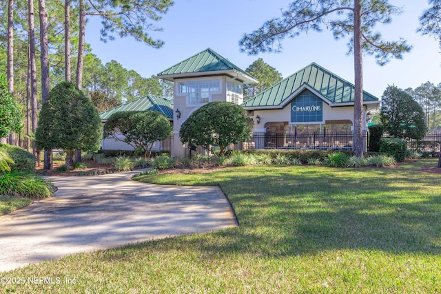 exterior space featuring a standing seam roof, stucco siding, a front lawn, and metal roof