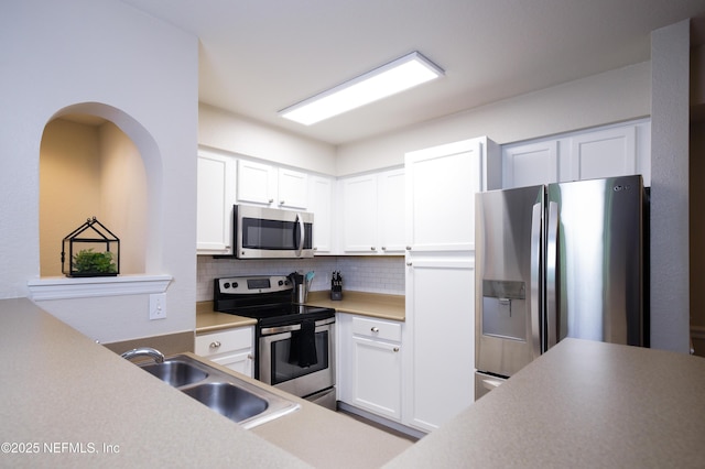 kitchen featuring white cabinets, a sink, backsplash, and appliances with stainless steel finishes