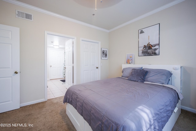 carpeted bedroom with ensuite bath, baseboards, crown molding, and visible vents