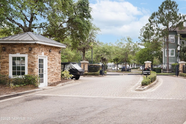 view of street with a gate, a gated entry, and curbs
