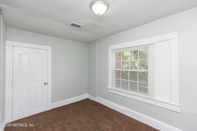 1488 W 5th St, Jacksonville, FL 32209 - spare room featuring a textured ceiling, dark colored carpet, visible vents, and baseboards