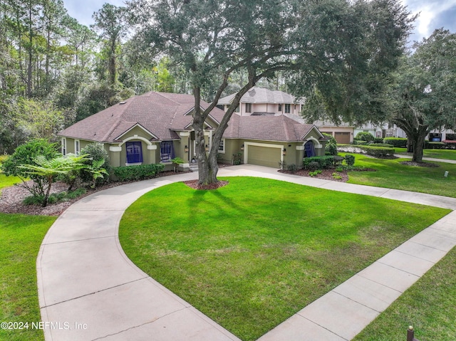 mediterranean / spanish-style home with an attached garage, driveway, a front lawn, and stucco siding