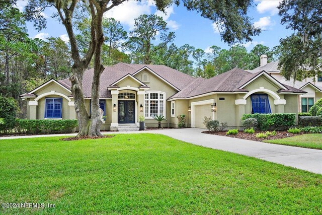 ranch-style home featuring stucco siding, a front lawn, driveway, and a garage