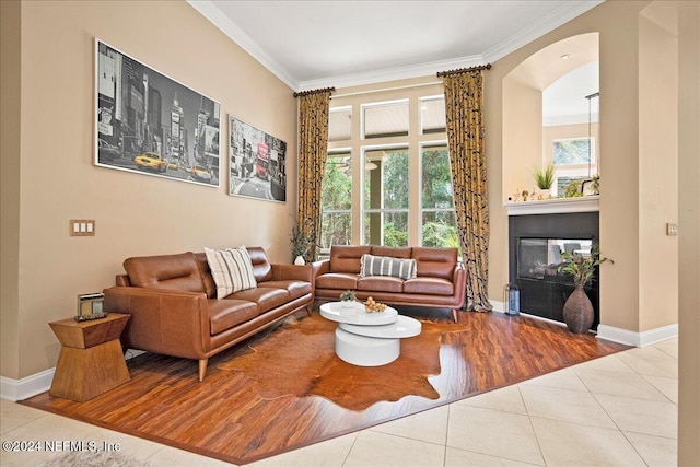 living area featuring arched walkways, tile patterned flooring, crown molding, and baseboards
