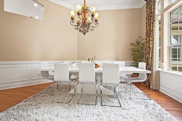 dining room with a decorative wall, crown molding, wood finished floors, and a chandelier