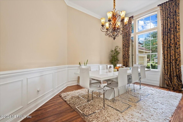 dining room featuring a wainscoted wall, crown molding, a notable chandelier, wood finished floors, and a decorative wall