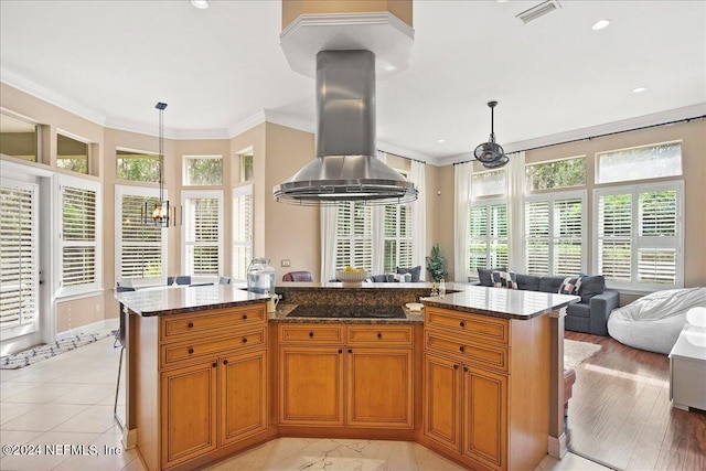 kitchen featuring black electric cooktop, island exhaust hood, dark stone countertops, an inviting chandelier, and ornamental molding