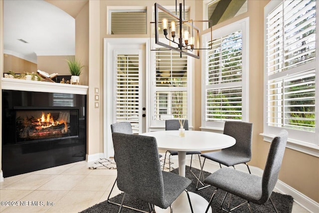 tiled dining space featuring an inviting chandelier, a glass covered fireplace, and baseboards