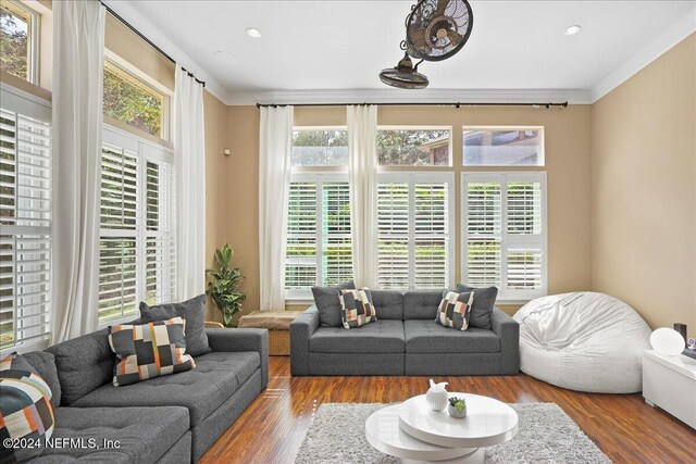 living room with wood finished floors, a wealth of natural light, and ornamental molding