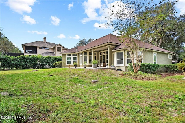 rear view of property featuring a yard and stucco siding