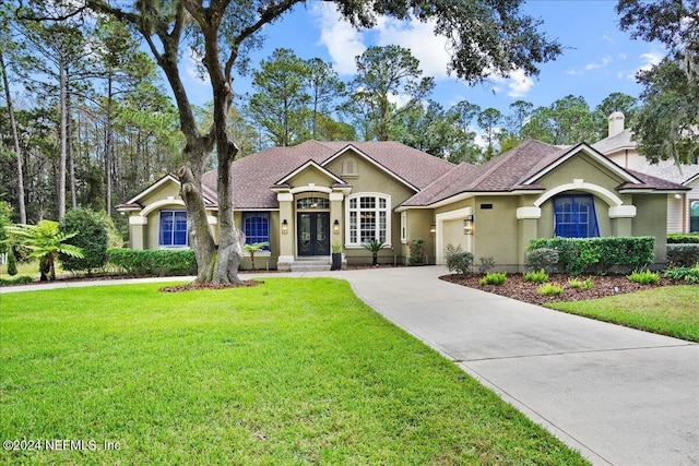 view of front of property with stucco siding, an attached garage, concrete driveway, and a front yard