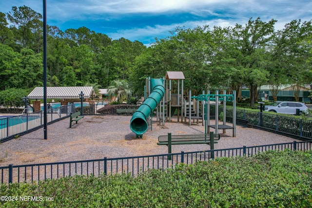 community jungle gym featuring a community pool and fence