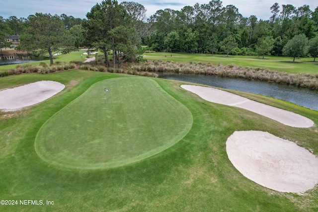 view of property's community with a yard, a water view, and golf course view