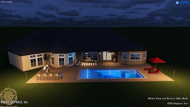 back of house at night featuring stucco siding, an outdoor pool, a yard, and a patio