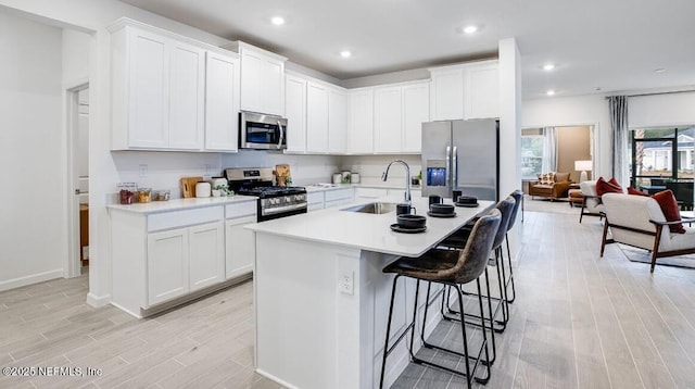 335 Dogleg Run, Saint Johns, FL 32259 - kitchen featuring stainless steel appliances, a sink, light wood-style floors, light countertops, and a breakfast bar