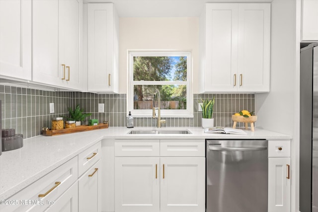 kitchen with light stone counters, a sink, white cabinetry, backsplash, and appliances with stainless steel finishes