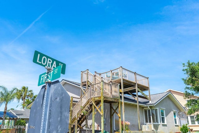 back of property featuring stucco siding, a wooden deck, stairway, and central AC unit