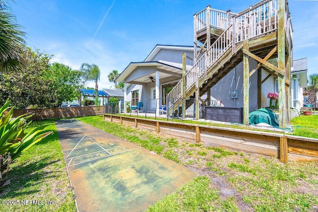 rear view of house with stairs, a ceiling fan, stucco siding, and a deck