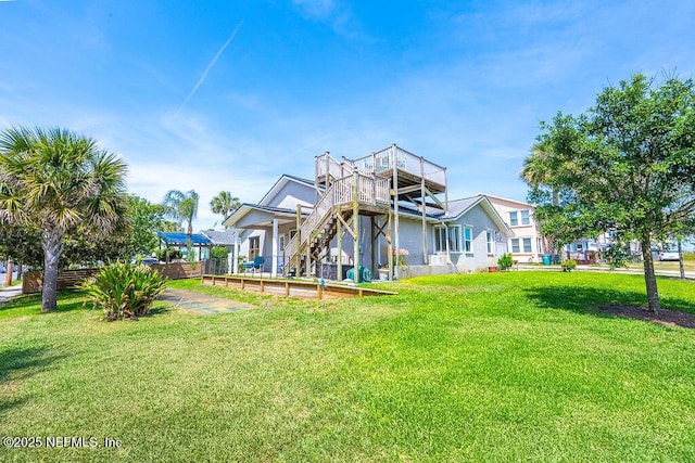rear view of house with a lawn, stairs, and a wooden deck