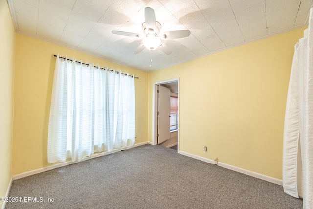 carpeted empty room with ceiling fan, baseboards, and crown molding