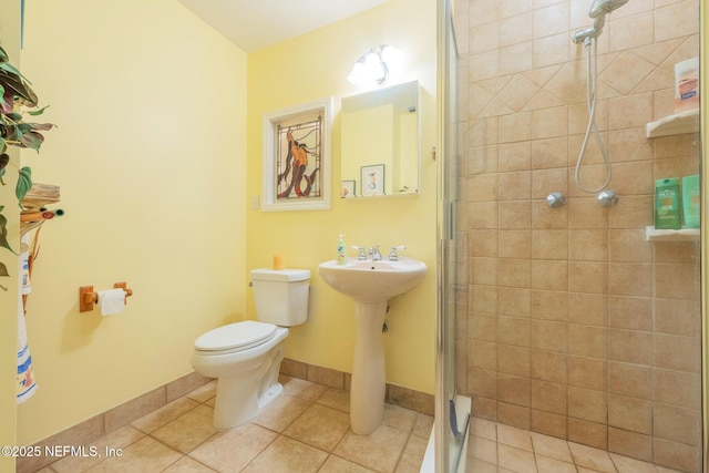 bathroom with a stall shower, tile patterned floors, toilet, and baseboards