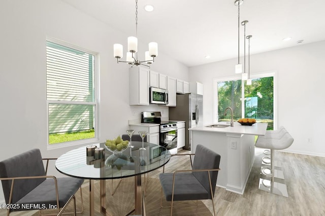 dining space featuring an inviting chandelier, baseboards, recessed lighting, and light wood-type flooring